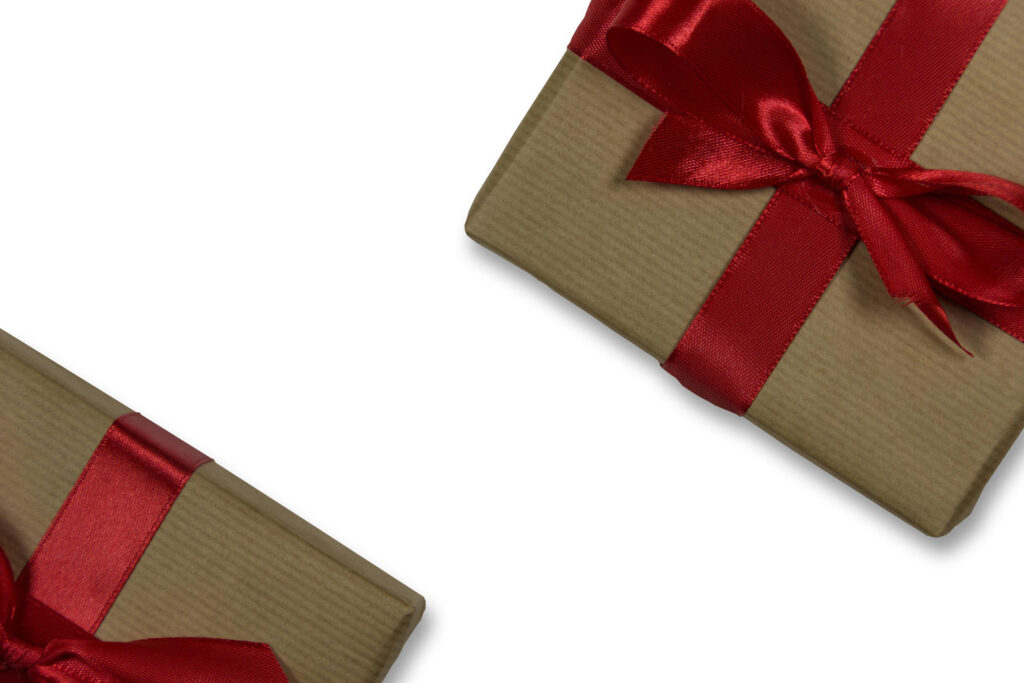 Two kraft-wrapped gift boxes tied with red ribbons on a light background.